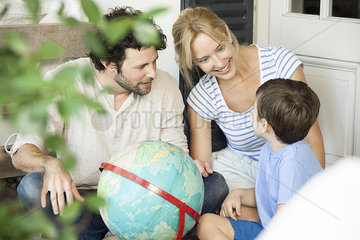 Family with one child looking at world globe together