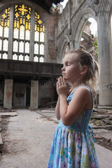 Little girl praying in ruined church