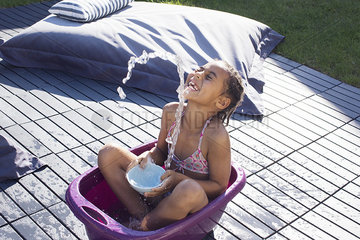 Girl sitting in bucket playing with water