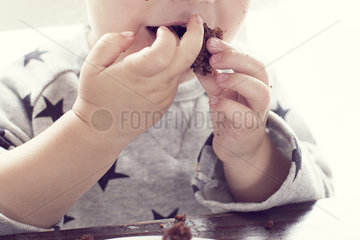 Child eating cake with hands