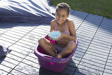 Girl sitting in bucket playing with water