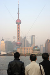 Shanghai  drei Maenner am Bund schauen auf Pudong