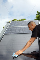 Berlin  Deutschland  Auszubildender putzt einen Solarkollektor