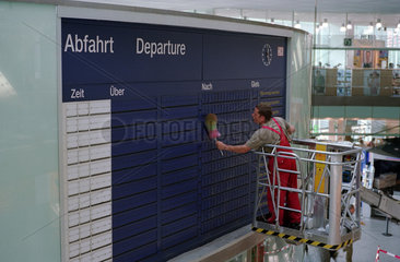 Arbeiter reinigt die Anzeigetafel der Zugverbindungen am Ostbahnhof in Berlin