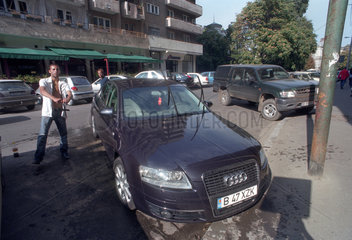 Junger Mann waescht ein Auto auf der Strasse in Bukarest