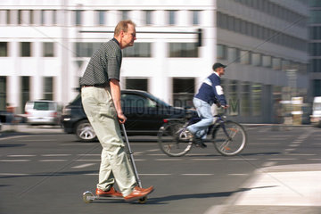Mann faehrt Roller im Stadtverkehr in Berlin