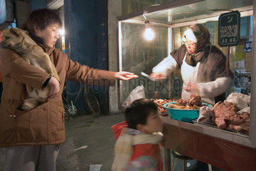 Peking  Haendlerin auf einem Markt reicht einer Kundin eine Kostprobe ihrer Ware