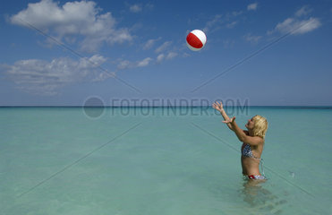 Junge Frau spielt mit einem Wasserball  Bahamas