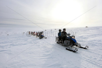 Saelen  Schweden  Maenner fahren auf Schneemobilen