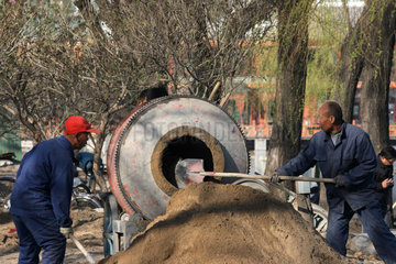 Peking  zwei Bauarbeiter schaufeln Kies in Zementmaschine