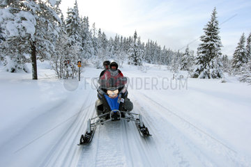 Saelen  Schweden  Maenner fahren auf einem Schneemobil
