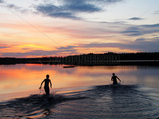Silvkoparen  Schweden  zwei Jungs baden bei Sonnenuntergang in einem See