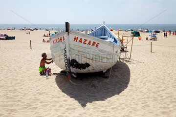 Nazare  Portugal  Mann repariert Holzboot am Strand von Nazare