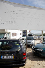 Nazare  Portugal  Verblichenes Bauschild und parkende Autos auf einem Parkplatz in Nazare