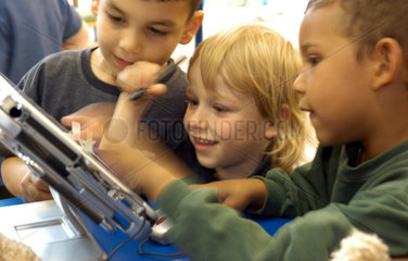 Kinder verschiedener Nationalitaeten lernen an einem Computer