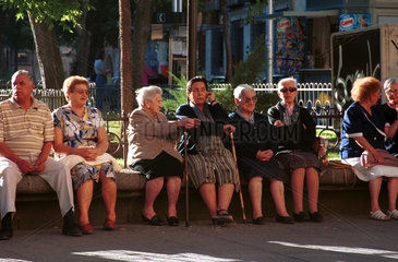 Aeltere Leute sitzen in der Sonne in Salamanca