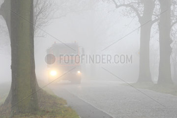 Wassmannsdorf  Deutschland  Autoverkehr auf einer Landstrasse bei Nebel