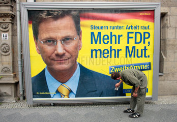 Berlin  Mann klebt Wahlplakat fuer die FDP