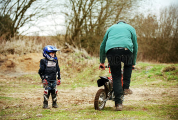 Vater hilft seinem Sohn beim Anlassen seines Motorrads  Norddeutschland
