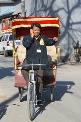 Peking  Rikschfahrer telefoniert mit dem Handy