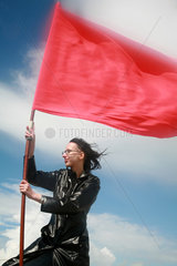Sankt Peter-Ording  Deutschland  eine Frau haelt eine rote Fahne im Sturm