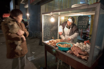 Peking  Haendlerin auf einem Markt bereitet Fleisch zu