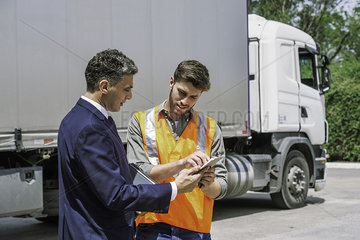 Worker and businessman discussing near lorry