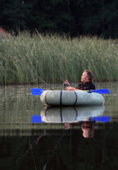 Wusterhausen  Deutschland  Sommerurlaub  Mann angelt von seinem Schlauchboot aus