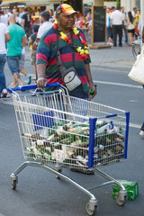 Berlin  Deutschland  schwarzhaeutiger Mann mit Deutschlandmuetze sammelt Pfandflaschen