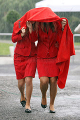 Hannover  Deutschland  Frauen schuetzen sich mit einer Decke vor einem Regenschauer