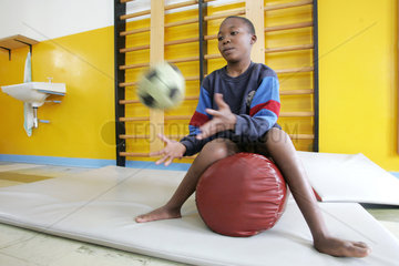 Kenia  ein behinderter Junge uebt einen Ball zu fangen