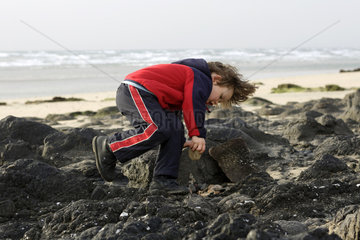 Pajara  ein Kind spielt mit Steinen am Strand