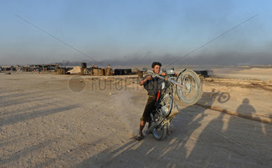 Deir ez-Zor  Syrien  Junge mit Motorrad auf einer Oelfoerderstelle zur Benzingewinnung