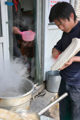 Peking  ein Mann hobelt Nudeln in kochendes Wasser
