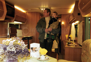 Ein Mann besichtigt mit einem Kleinkind einen Wohnwagen