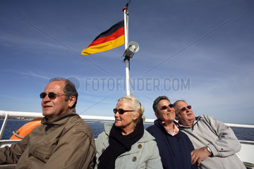 Touristen und Deutschlandfahne auf Schiff auf der Ostsee