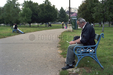 Mann liest auf einer Bank im Izvor-Park  Bukarest  Rumaenien