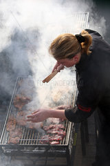 Hannover  Deutschland  Frau bereitet Fleisch auf einem Grill zu