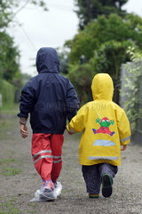 Berlin  Kinder in Regenkleidung laufen Hand in Hand