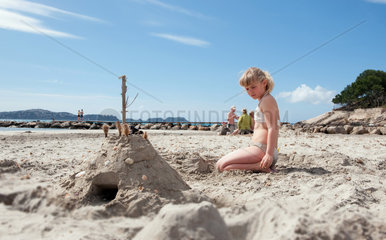 Peguera  Mallorca  Spanien  ein Maedchen baut eine Sandburg