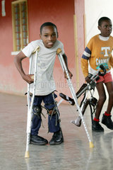 Kenia  Ein Junge stuetzt sich auf seine Metallkruecken
