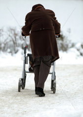 Berlin  Deutschland  Seniorin mit Rollator laeuft einen schneebedeckten Gehweg entlang