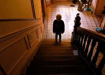 Ein kleiner Junge steht traurig auf einer Treppe