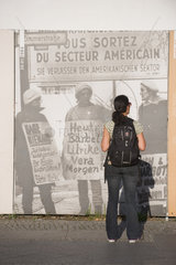 Berlin  Deutschland  eine Frau vor einem Bild der DDR Ausstellung am Checkpoint Charlie