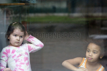 Berlin  Maedchen schauen aus einem Fenster