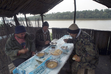 Einheimische essen eine Fischsuppe an der Donau  Rumaenien