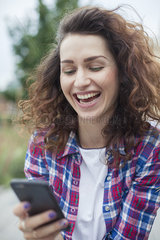 Young woman laughing while text messaging outdoors