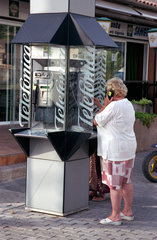 Eine aeltere Dame an einer Telefonzelle auf Mallorca