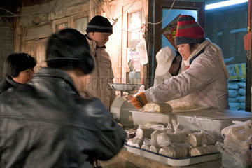 Peking  Haendlerin auf einem Markt verkauft ihre Ware