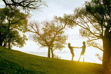 Couple holding hands in park  backlit by sunlight